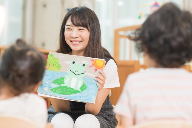 笑顔で紙芝居を読む保育士の女性