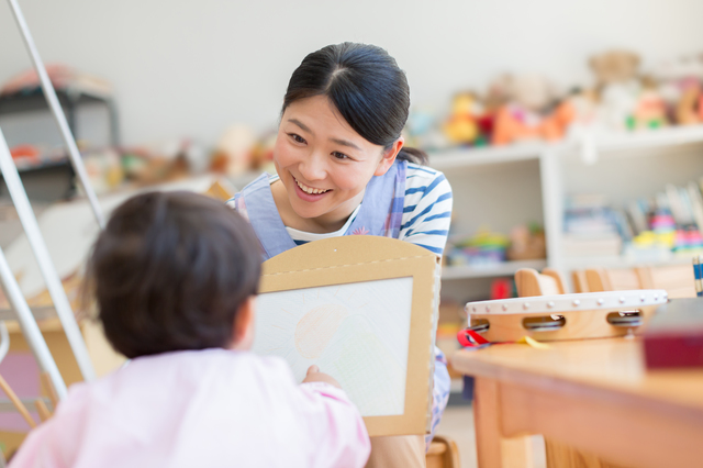 子供と笑顔で接している保育士