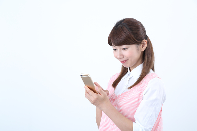 スマートフォンを見る保育士の女性