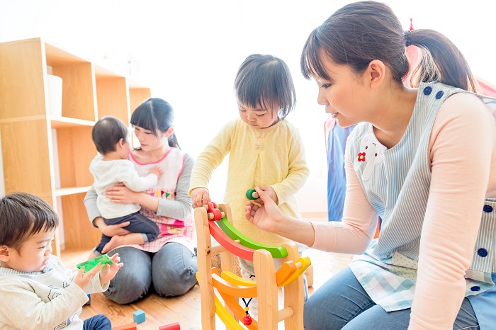 子どもたちとおもちゃで遊ぶ保育士