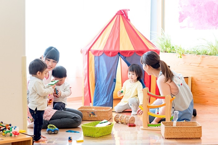 認定こども園で3人の子供と遊ぶ2人の保育士